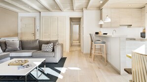 A modern living room with a sofa, coffee table, and a kitchen area with a bar counter. - Luderna - Apartamento Val de Ruda B25 Sarraèra (Baqueira)