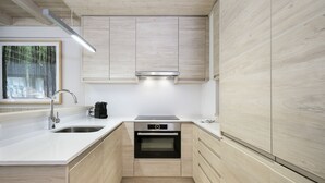 A modern kitchen with wooden cabinetry, a stainless steel sink, and an integrated oven.