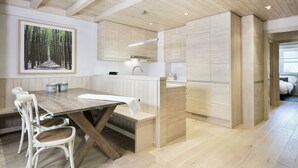 A modern kitchen with wooden cabinets, a dining table with chairs, and a painting on the wall.
