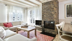 A living room with a stone fireplace, a sofa, a coffee table, and a TV.