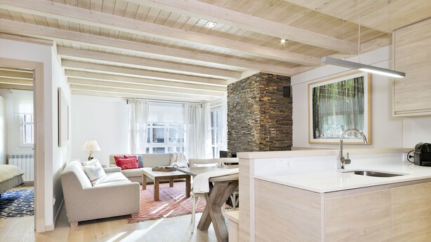 A modern kitchen with a stone accent wall, wooden beams, and a large window.