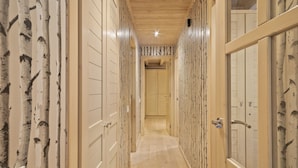 A hallway with wooden walls and doors, leading to a room with a wooden ceiling and a visible door. - Luderna - Val de Ruda B52 dera Montjòia (Baqueira)
