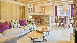 A cozy living room with a sofa, coffee table, and dining area with chairs. - Luderna - Val de Ruda B52 dera Montjòia (Baqueira)