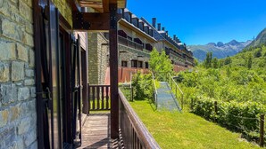 A wooden balcony with stone walls, a view of a mountain range, and a vineyard. - Luderna - Val de Ruda B52 dera Montjòia (Baqueira)