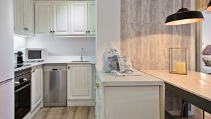Een moderne keuken met witte kasten, roestvrijstalen apparatuur en een houten accentmuur.