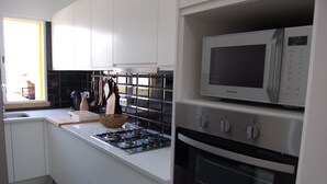 Ett modernt kök med vita skåp, en gasspis, en mikrovågsugn och en ugn.