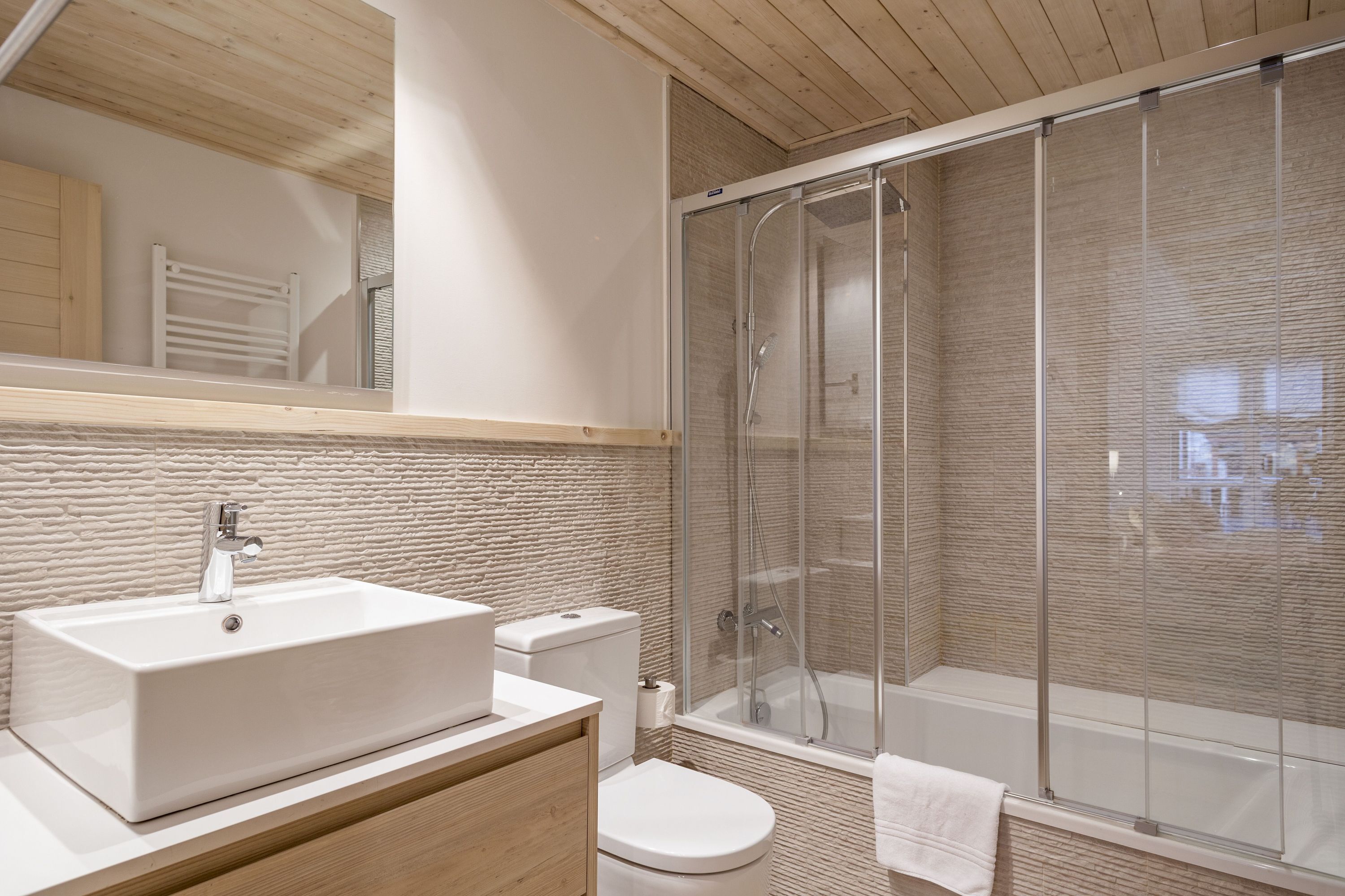 Une salle de bain moderne dotée d’un grand lavabo, de toilettes et d’une douche à l’italienne.