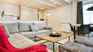Un salon moderne avec un canapé, une table basse et un coin repas avec des chaises.
