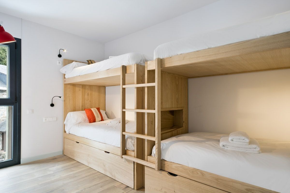 Une chambre avec un lit superposé, une petite échelle, un petit bureau et une fenêtre.