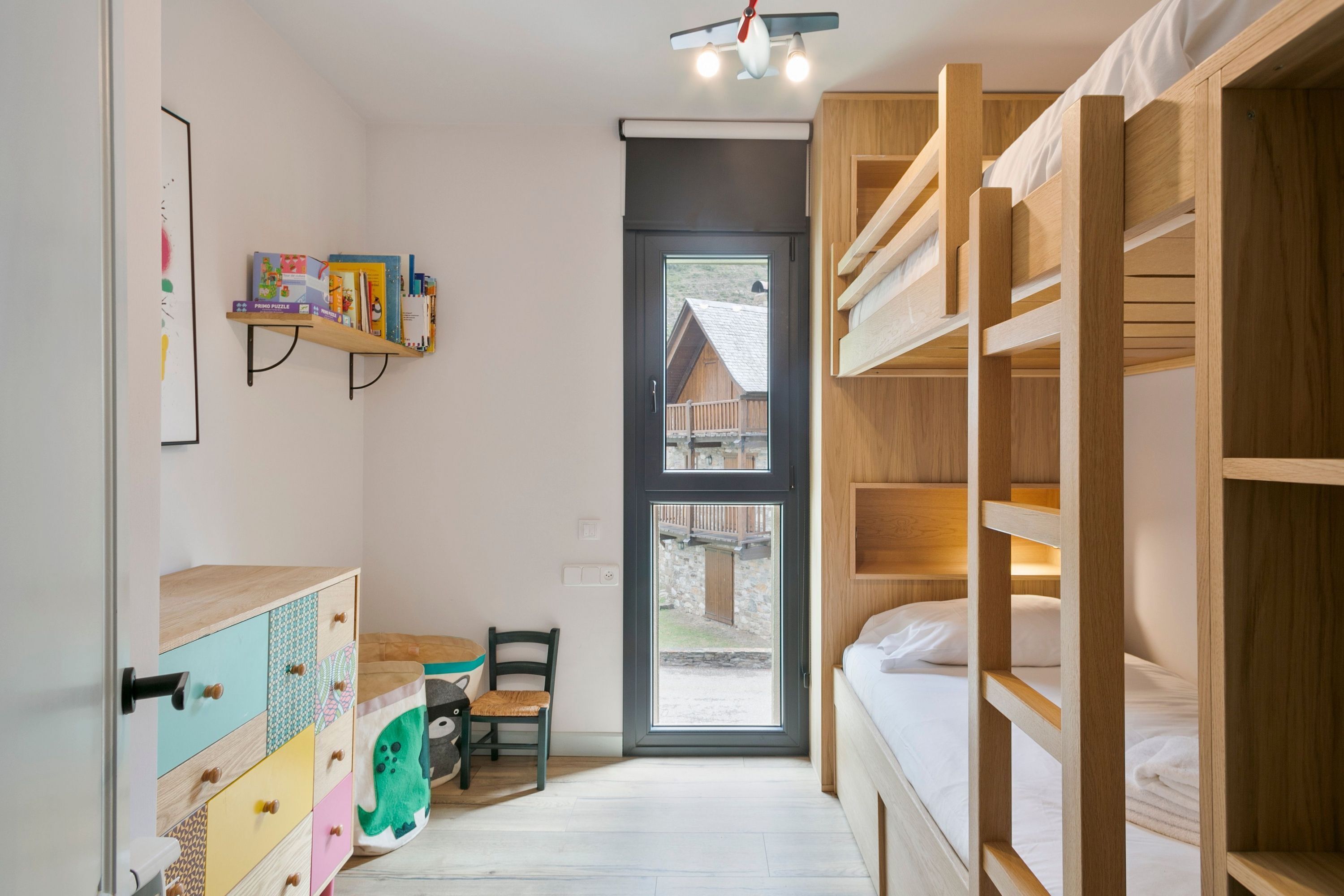 A compact room with bunk beds, a desk with a chair, and a bookshelf.