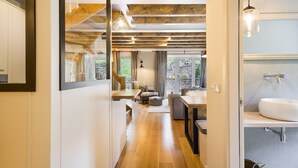 Ein modernes Interieur mit Holzboden, Essbereich, einer Couch und einem Badezimmer mit Waschbecken.
