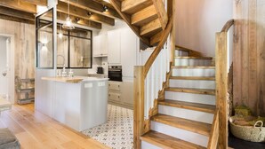 Eine moderne Küche mit Holzbalken, einer zentralen Kochinsel und einer Treppe.