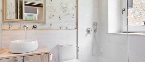 A modern bathroom with a white sink, toilet, and shower.