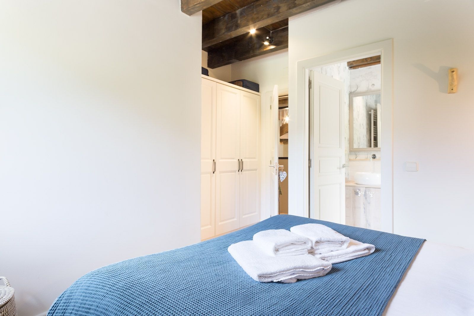 A bedroom with a bed, a wardrobe, and a bathroom visible through an open door.
