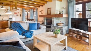 Una sala de estar acogedora con chimenea, televisor y comedor con muebles de madera.