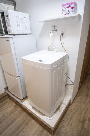 Compact kitchen with a refrigerator, washing machine, and storage space.