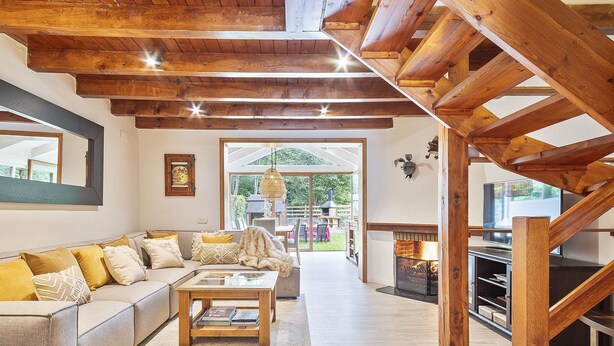 A spacious living area with a wooden ceiling, a sofa with cushions, a coffee table, and a fireplace. - Luderna - Casa con jardín Vista Aneto (La Val d'Aran)