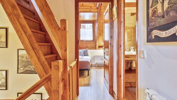 Una escalera de madera que lleva a un dormitorio con una cama, una mesita de noche y una ventana.
