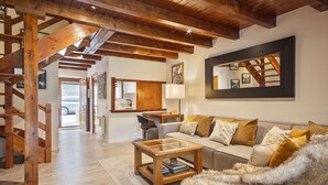 A spacious living room with a wooden staircase, a sofa set, a coffee table, and a large mirror. - Luderna - Casa con jardín Vista Aneto (La Val d'Aran)