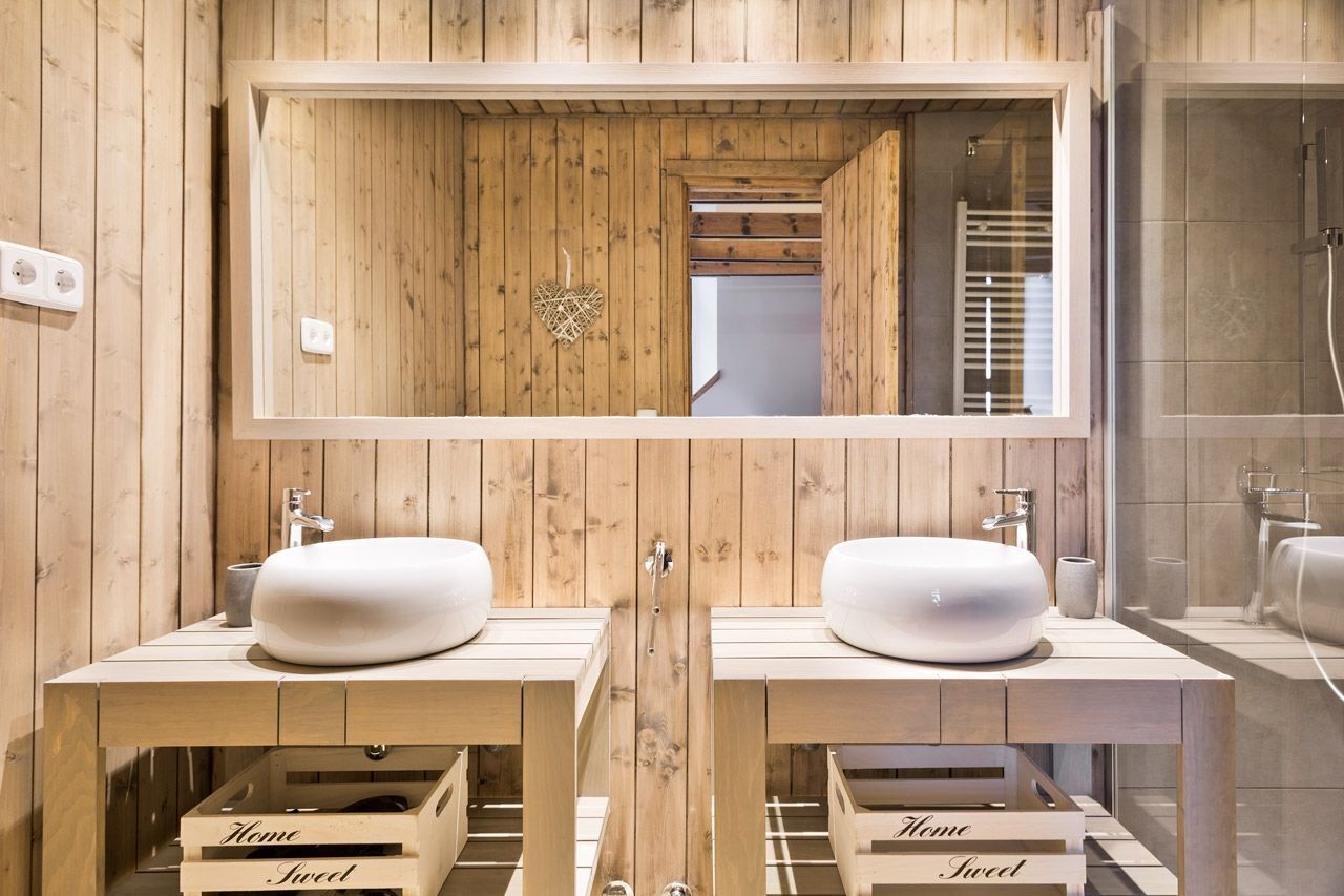 A wooden bathroom with two sinks, a mirror, and a shower.