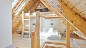 A high-ceilinged attic bedroom with exposed wooden beams, a loft bed, and a glass partition. - Luderna - Val de Ruda C23 Barbacans (Baqueira)