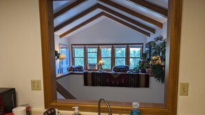 A kitchen with a large window, wooden beams, and a sink with various items on the counter. - Durango Treehouse | Mountain Views | Hot Tub (Durango)
