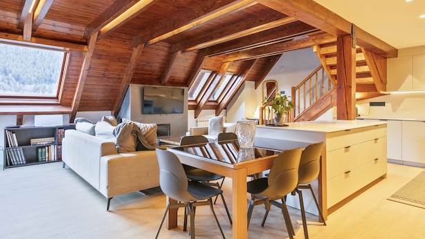 Un espacio habitable moderno estilo loft con comedor, cocina y una escalera que lleva a un nivel superior.