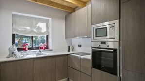Une cuisine moderne avec des meubles en bois, un four à micro-ondes en acier inoxydable et un four traditionnel.