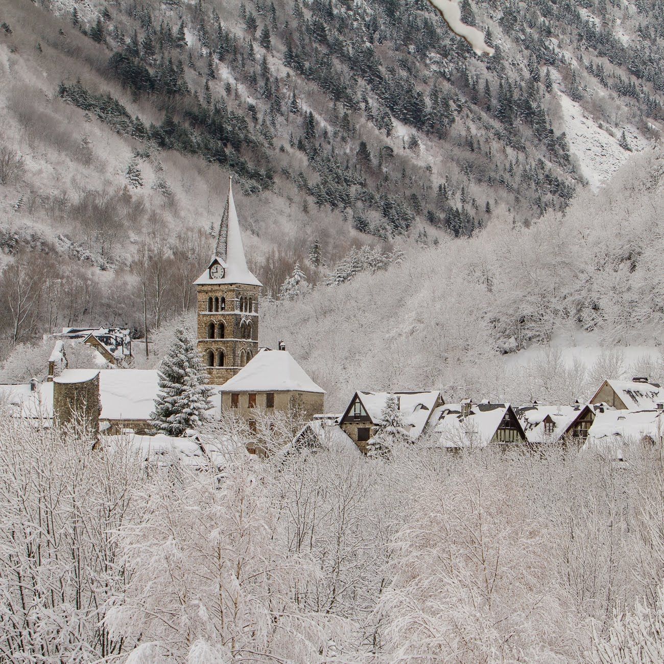 A snow-covered village with a prominent church tower and traditional houses.