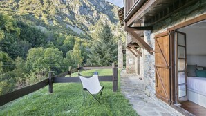 Un chalet de montagne rustique, avec une façade en pierre, un balcon en bois et une vue sur une vallée verdoyante.