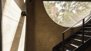 A concrete staircase with a metal handrail leading to an upper level.