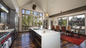 Een moderne keuken met een groot eiland, roestvrijstalen apparatuur en uitzicht op het groen.