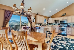A spacious kitchen with wooden cabinets, a dining table, and a chandelier.