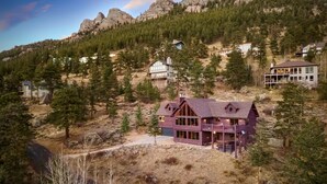 Ein mehrstöckiges Haus mit einem markanten Balkon, eingebettet in eine bewaldete Berglandschaft.