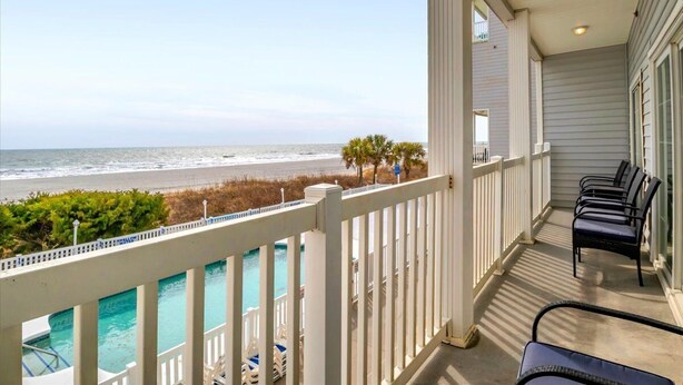 A balcony with a view of the ocean, a pool, and a row of chairs. - PierWatch I 103 | Oceanfront Six Bedroom Condo (North Myrtle Beach)