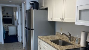 A kitchen with white cabinets, a stainless steel refrigerator, a microwave, a sink, and a stove. - Ocean Front Resort in North Myrtle Beach,  Sleeps 6, Directly on the Beach! (North Myrtle Beach)