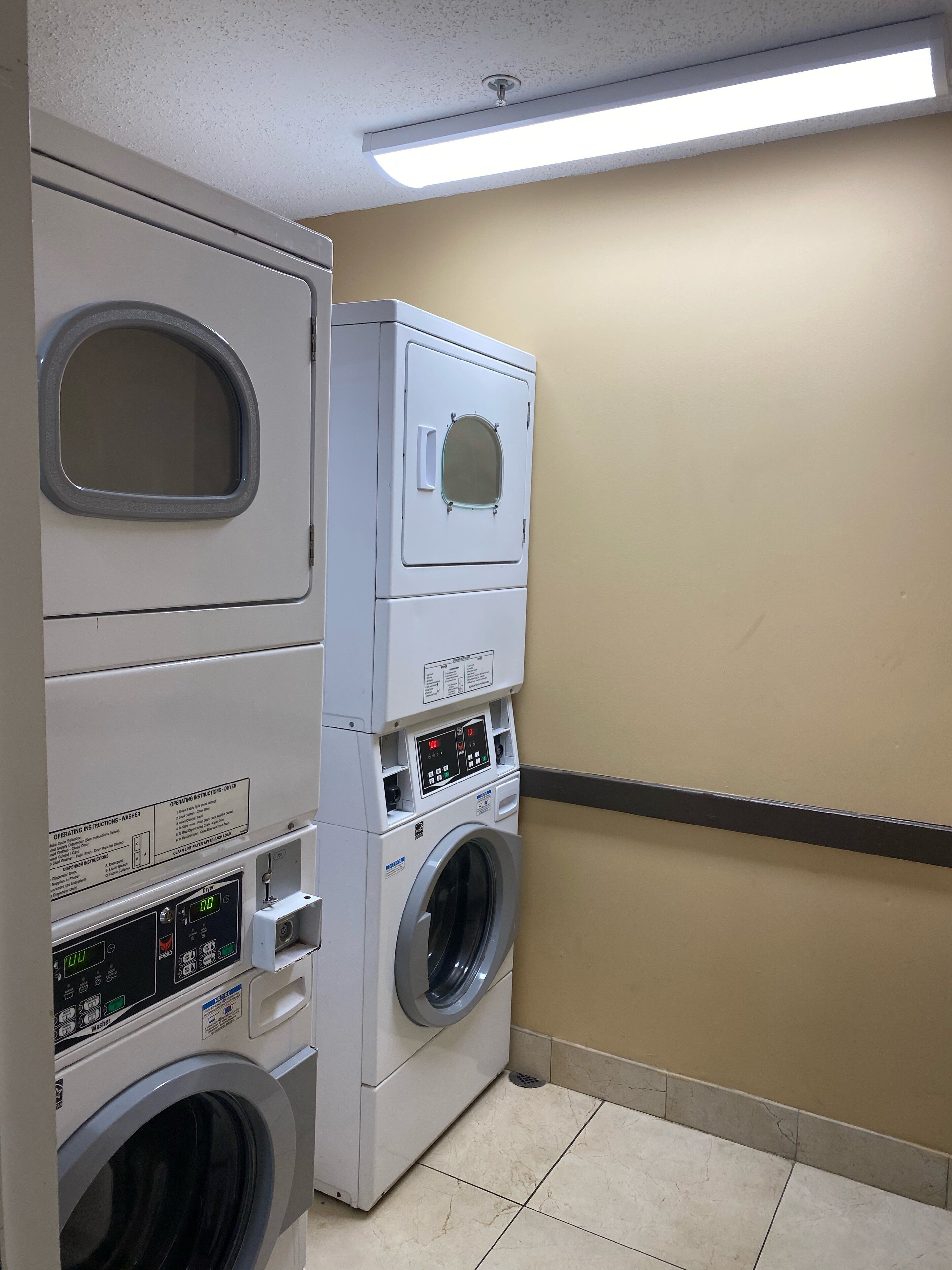 A laundry room with a front-loading washer and dryer, control panel, and instructions.