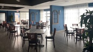 A spacious dining area with multiple tables and chairs, large windows, and a ceiling fan. - Ocean Front Resort in North Myrtle Beach,  Sleeps 6, Directly on the Beach! (North Myrtle Beach)