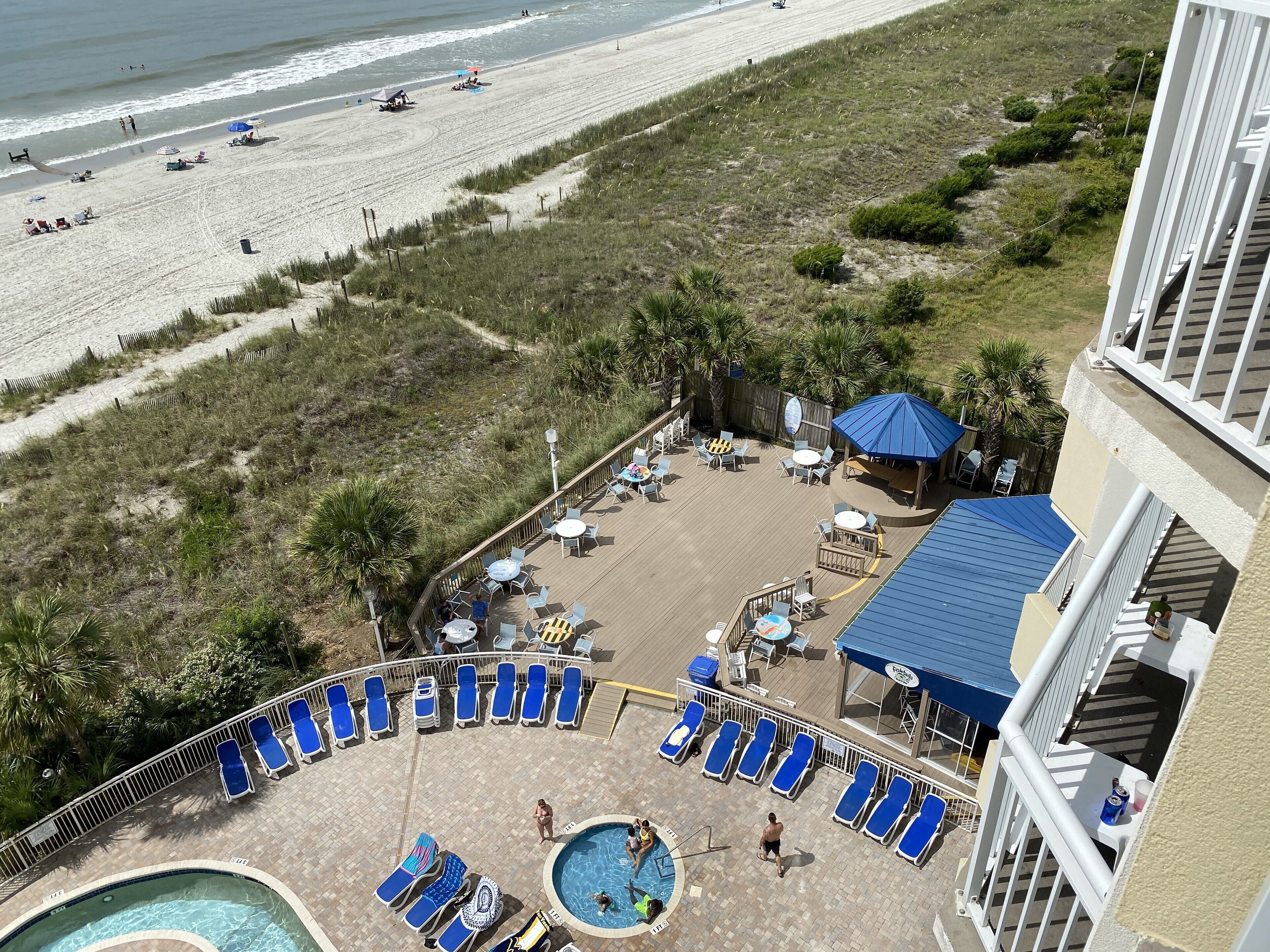 A resort with a pool, lounge chairs, and a beach view.