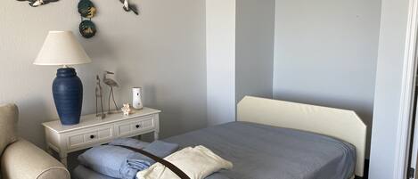 Et hotelværelse med en seng, et natbord, en lampe og billedkunst på væggen.
