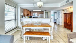 Une cuisine spacieuse avec un coin repas, comprenant un îlot central, des meubles blancs et un lustre.