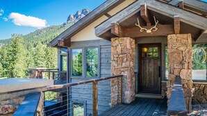 A mountain lodge with a stone facade, wooden deck, and a deer head sculpture. - Hyler Mountain Lodge Vacation Home at Windcliff (Estes Park)