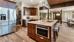A modern kitchen with stainless steel appliances, wooden cabinets, and a central island with bar stools. - Hyler Mountain Lodge Vacation Home at Windcliff (Estes Park)