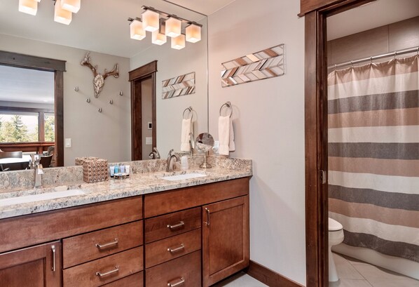 A bathroom with a double sink vanity, a mirror, and a shower curtain.