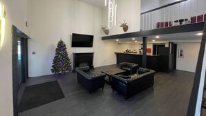 A modern living room with a fireplace, a Christmas tree, and a flat-screen TV. - Guest Lodge (Minot)