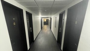 A long, narrow hallway with dark wooden floors and white walls. - Guest Lodge (Minot)
