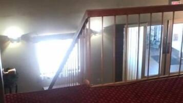 Un área con alfombra roja y una escalera que lleva a una habitación más luminosa.