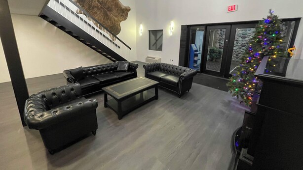 A modern lobby with a staircase, leather sofas, a coffee table, and a Christmas tree. - Guest Lodge (Minot)
