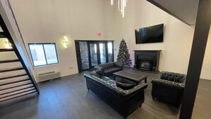 A modern living room with a fireplace, a large TV, and a Christmas tree. - Guest Lodge (Minot)