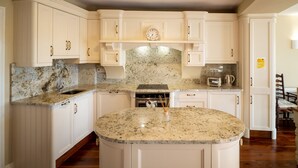 A kitchen with white cabinets, granite countertops, a built-in oven, and a clock on the wall. - Cottage 360 - Clifden - sleeps 6 guests  in 3 bedrooms (Clifden)